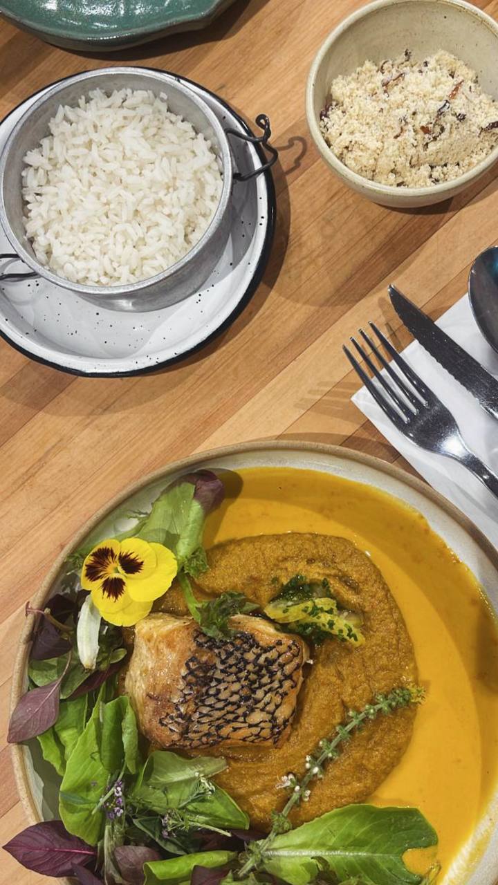 Prato gourmet com carne em molho dourado, salada decorada com flor comestível, arroz e acompanhamentos